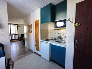 A compact kitchen with a microwave, sink, and wooden cabinets. - Studio with balcony near the chairlift (Uvernet-Fours)
