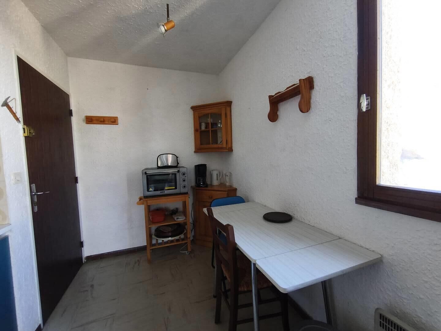 Une petite cuisine équipée d’une table, d’un four à micro-ondes, d’une bouilloire et d’un placard.