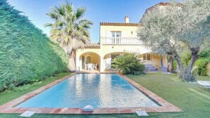 A swimming pool with a tiled border, a building with a balcony, and a well-maintained lawn. - Villa with heated pool in Sainte-Maxime (Sainte-Maxime)