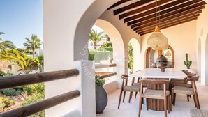 Eine Außenpatio mit rundem Tisch und Stühlen, einer hängenden Leuchte und Blick auf die umliegende Landschaft.