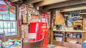 Eine Vintage-Küche mit einem roten Kühlschrank, Holzschränken und einer Backsteinwand.