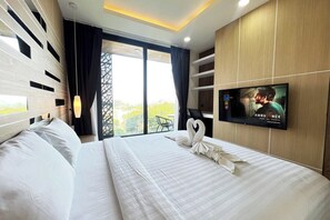 Ein Hotelzimmer mit Bett, Wandfernseher und Blick durch das Fenster.