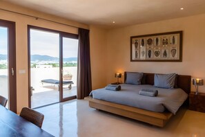 Un dormitorio con cama, mesa de comedor y vista al exterior.