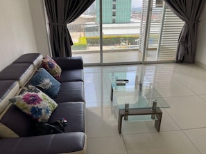 A modern living room with a sofa, glass coffee table, and large windows with curtains. - KSL 2BR #10 (Johor Bahru)