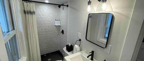 A compact bathroom with a toilet, sink, and shower area.