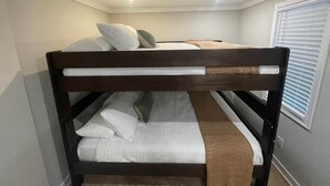A bunk bed with pillows and a blanket, a window with blinds, and a ceiling light.