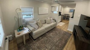 A living room with a sofa, a coffee table, a TV, and a ceiling fan.