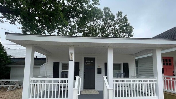 A white building with a porch, a black door, and a small mailbox.
