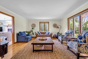 Un salon spacieux avec une table basse en bois, deux canapés et une grande fenêtre offrant une vue sur la verdure.