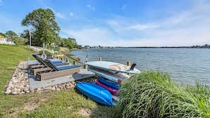 En terrass vid sjön med solstolar, kajaker och en SUP-bräda (bräda för stående paddling).