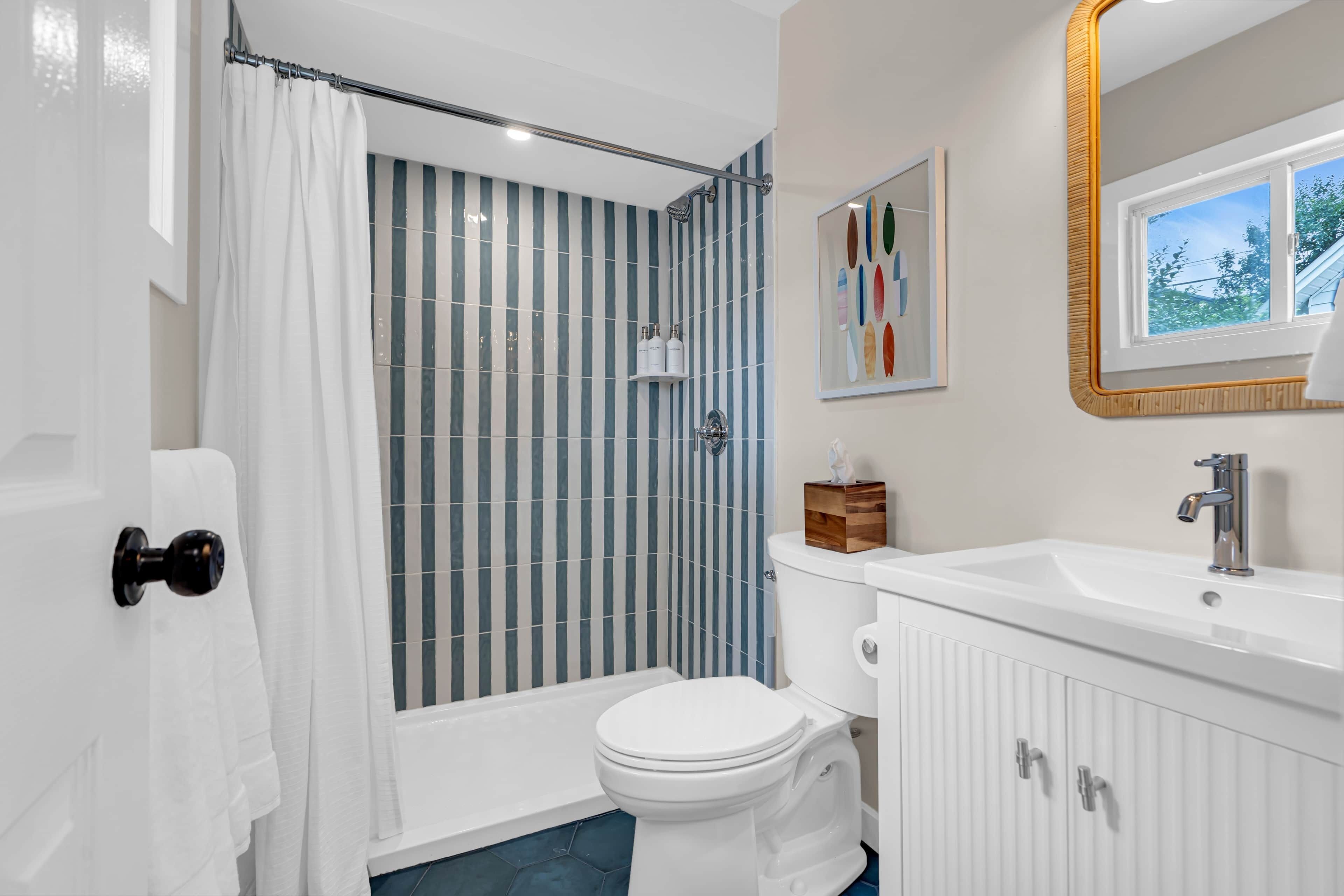 Un baño con ducha, inodoro, lavabo y ventana.