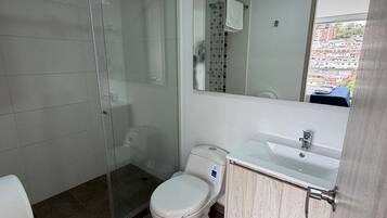 Un bagno moderno con cabina doccia in vetro, un water, un lavabo e uno specchio.