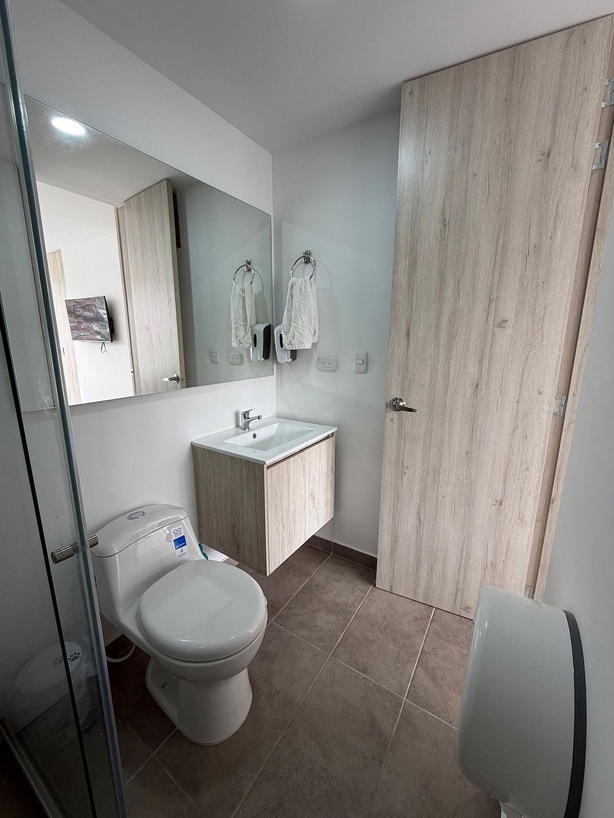 Een moderne badkamer met toilet, wastafel en spiegel.