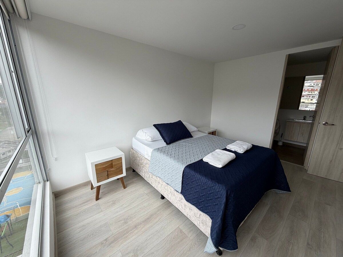 A bedroom with a bed, bedside tables, a wardrobe, and a window.