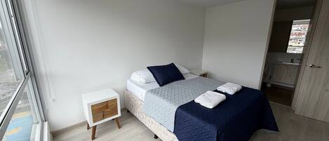 A bedroom with a bed, bedside tables, a wardrobe, and a window.