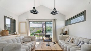 Una sala de estar moderna con un sofá modular, una mesa de centro de madera e iluminación colgante.