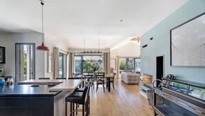 Una cocina moderna con una isla central, comedor con sillas y un ventanal grande.