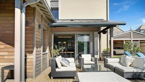 Un patio con mobiliario exterior, una puerta de cristal y un coche estacionado al fondo.