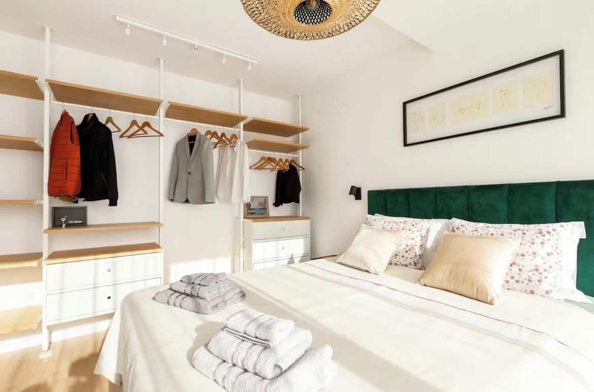A bedroom with a bed, a wardrobe, and a green upholstered headboard.