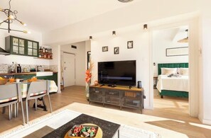 A modern living room with a TV, dining area, and a green accent wall. - SamoTako apartment (Split)