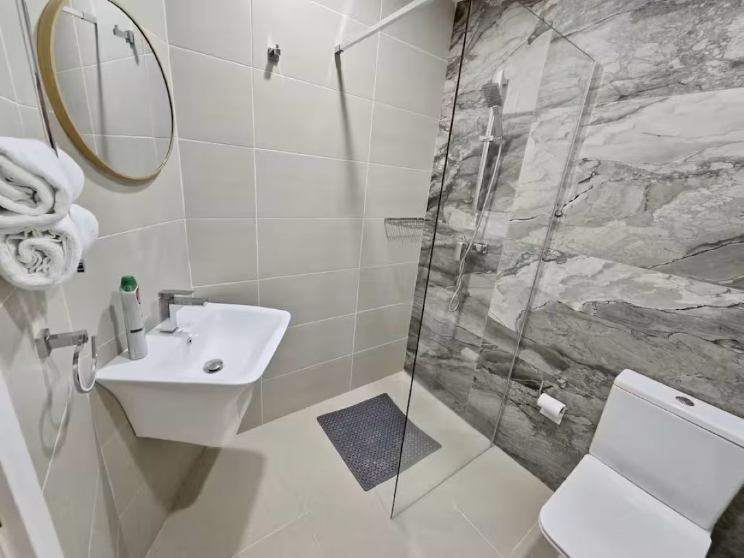 A bathroom with a glass-enclosed shower, a sink, and a toilet.