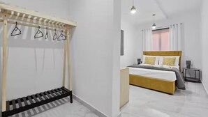 Een moderne slaapkamer met een bed, een houten bankje en een kledingrek.