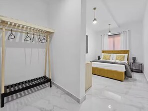 Ein modernes Schlafzimmer mit einem Bett, einer hölzernen Bank und einem Kleiderständer.