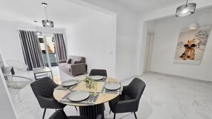 Een moderne eetruimte met een ronde tafel, zwarte stoelen en een glazen scheidingswand.
