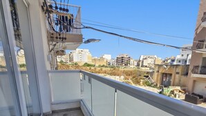 Een balkon met uitzicht op een stadsgezicht, een betegelde vloer en een balustrade.