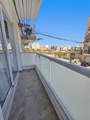 Ein Balkon mit Blick auf eine Stadtansicht, einem Fliesenboden und einem Geländer.