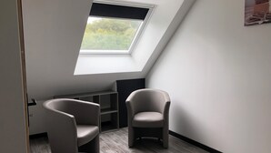A room with a skylight, two chairs, a dark-colored shelf, and a painting on the wall. - Gite Eltiwen esprit bar (la croix hellean)