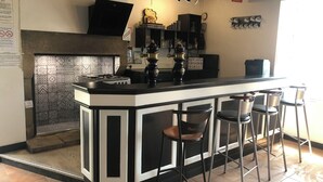 A bar area with a black and white bar counter, stools, a vintage espresso machine, and a tiled backsplash. - Gite Eltiwen esprit bar (la croix hellean)