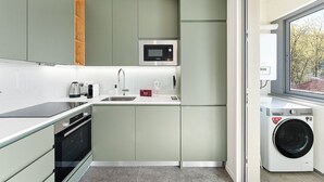 Cocina compacta con microondas, lavaplatos y lavadora.