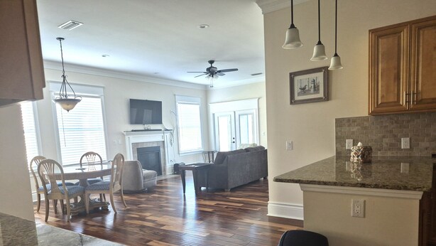 A spacious living area with hardwood flooring, a fireplace, a dining set, and a kitchen with granite countertops. - Cozy 2-bedroom villa in marvelous Fort Myers with AC (Fort Myers)