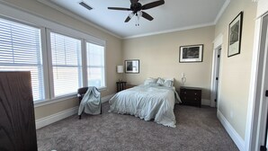 A bedroom with a bed, a ceiling fan, a chair, a nightstand, and a window with blinds. - Cozy 2-bedroom villa in marvelous Fort Myers with AC (Fort Myers)