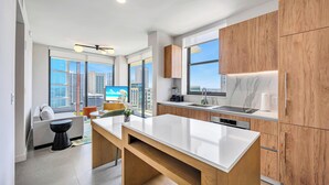 A modern kitchen with a central island, wooden cabinets, and large windows offering city views. - The Crosby (Miami)