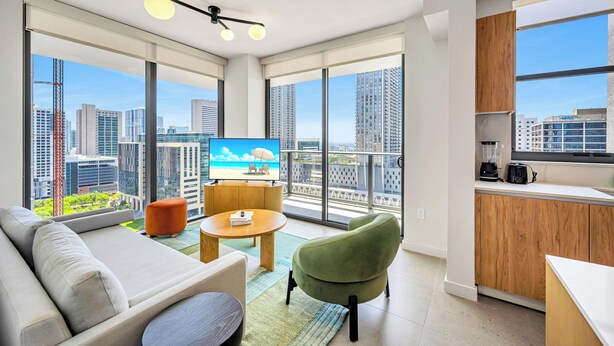 A modern living room with a sofa, a green armchair, a coffee table, and a TV. - The Crosby (Miami)