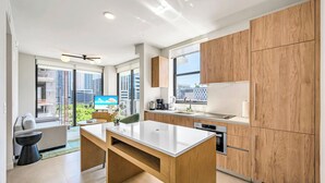 A modern kitchen with wooden cabinets, a central island, and a view of the city. - The Crosby (Miami)