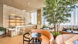 A modern interior with a bar area, seating, and a large tree. - The Crosby (Miami)
