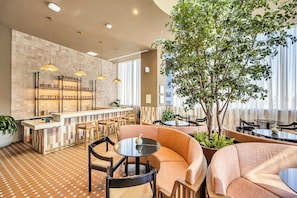 Un interior moderno con una zona de bar, asientos y una gran palmera.