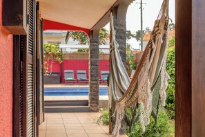 A covered outdoor area with a hammock, a pool, and red walls. - Aroeira Pool House by lisbon-coast vacation (Charneca da Caparica)
