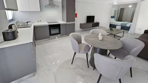 Eine moderne Küche mit Essbereich, einem Flachbildfernseher und einem Sofa im Wohnzimmer.