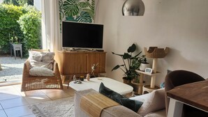 A living room with a sofa, a television, a wooden cabinet, and a plant. - Cosy apartment (Nîmes)