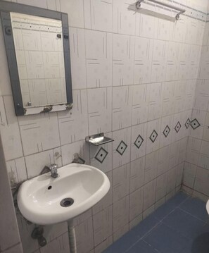 A bathroom with a white sink, a mirror, and patterned tiles. - Saalak Lite Social Palace  (Ukhimath)