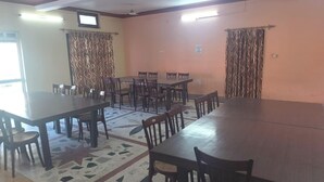 A conference room with multiple tables and chairs, a patterned floor, and a ceiling fan. - Saalak Lite Social Palace  (Ukhimath)