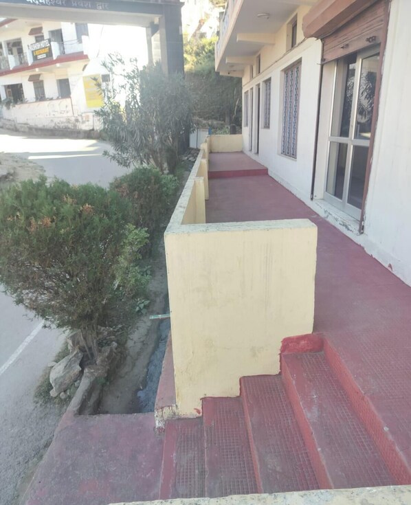 A hotel with a red and yellow exterior, a visible staircase, and a road in the background. - Saalak Lite Social Palace  (Ukhimath)