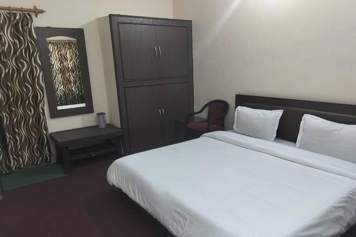 A hotel room with a bed, a desk, a wardrobe, and a chair.