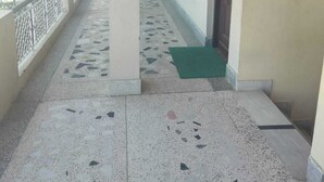 A covered corridor with tiled flooring, columns, and doors. - Saalak Lite Social Palace  (Ukhimath)