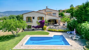 Una casa de dos pisos amb piscina, mobiliari d'exterior i jardí.