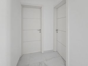 A hallway with two white doors, one with a keyhole and the other with a handle. - Centrally located, well finished two bedroom, 1 bathroom apartment (San Pawl il-Baħar)